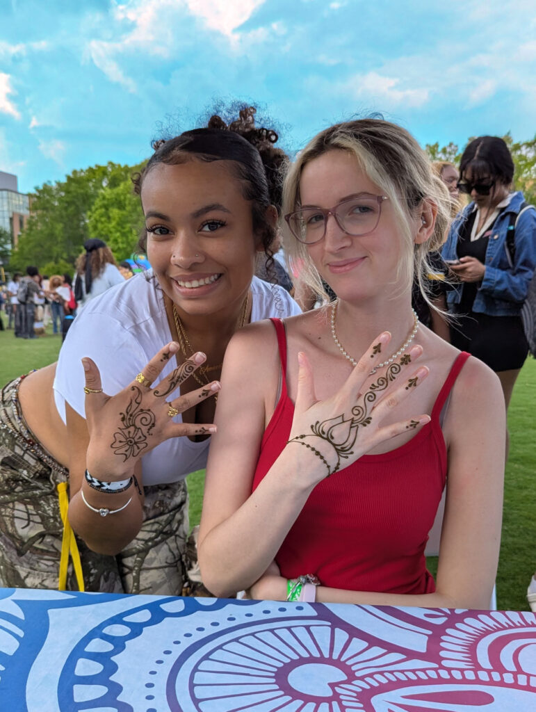 Two college students holding up their hands to show off henna stains.