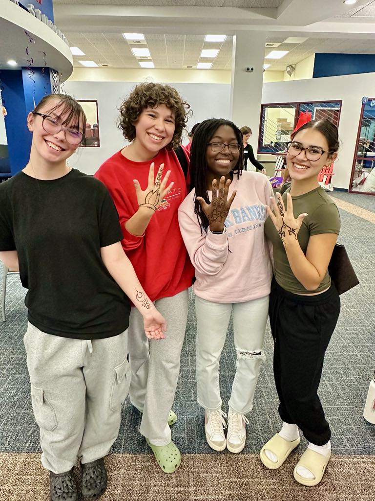 Four students showing off their henna designs with big smiles