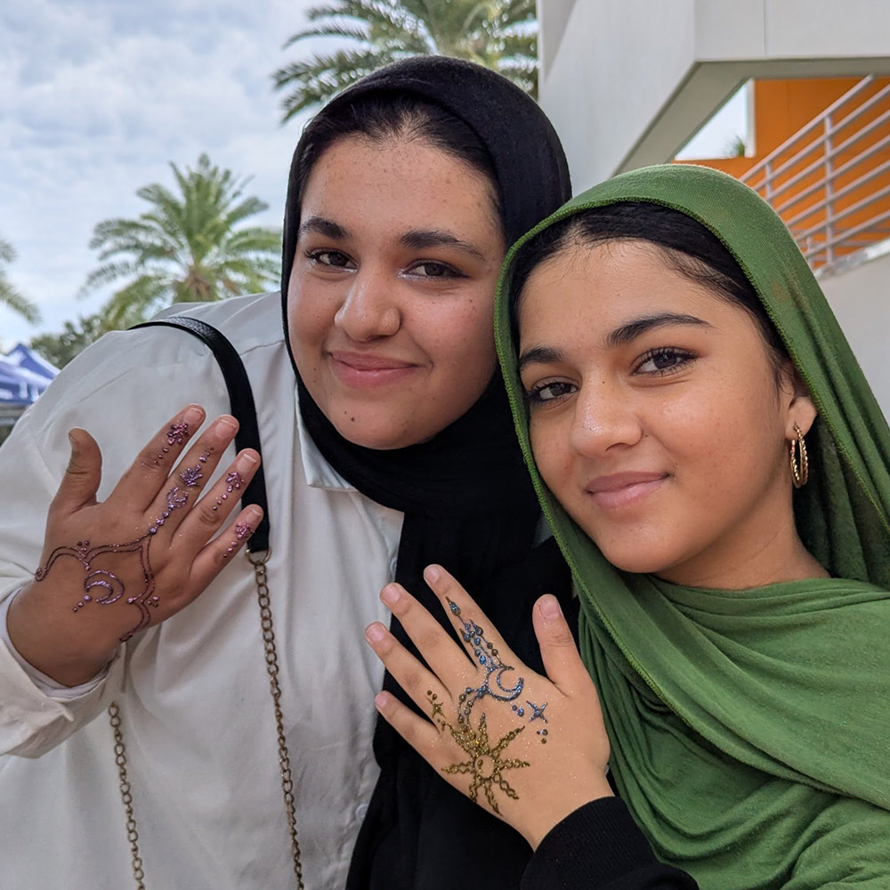 Two Muslim students showing off henna designs