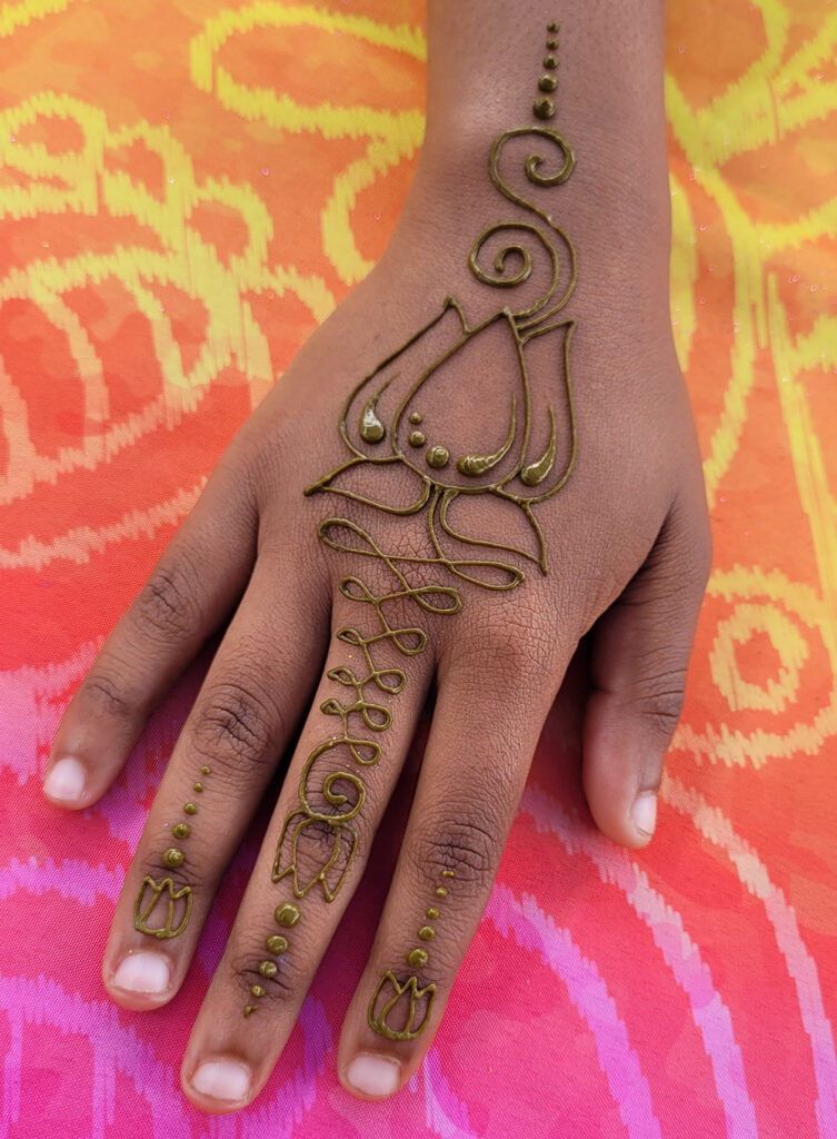 Beautiful lotus henna design with fresh wet henna on top of a hand.