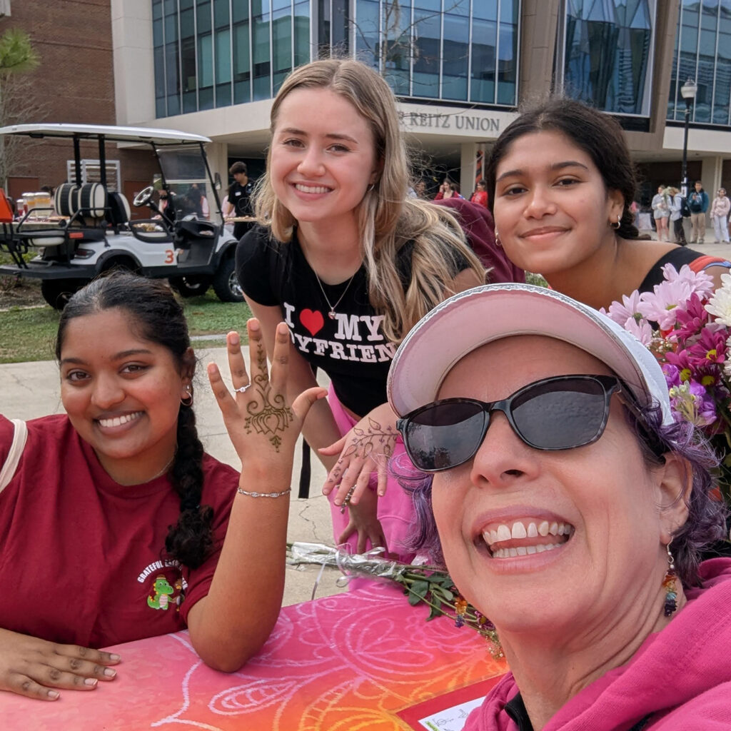 Jody with 3 students getting henna at a campus Valentine event.