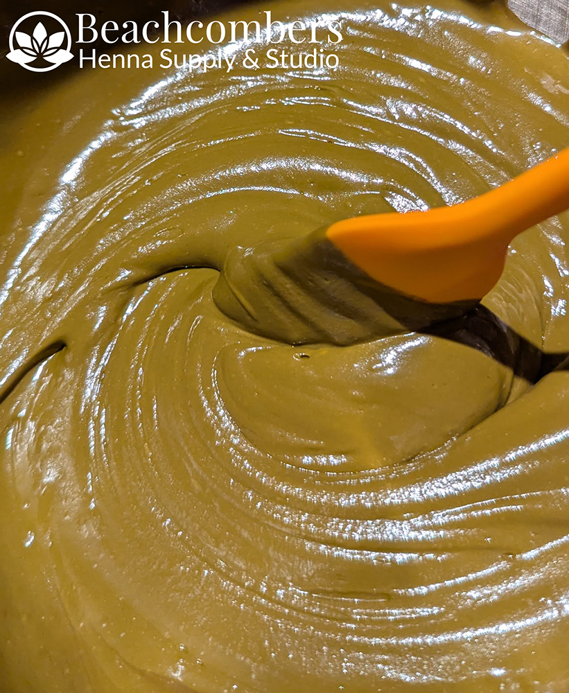 Freshy mixed ORa henna paste in a bowl with a spatula.
