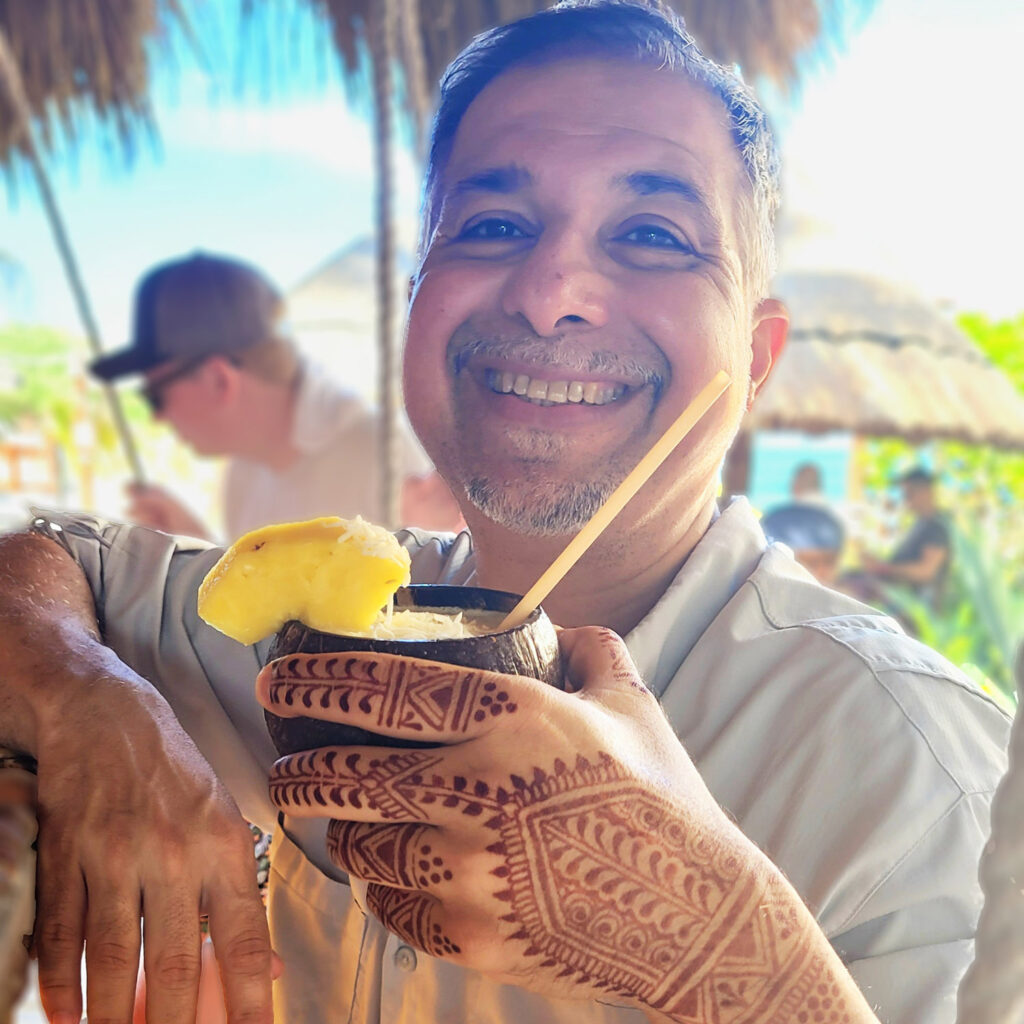 A man holding a drink while showing off his hennaed hand.