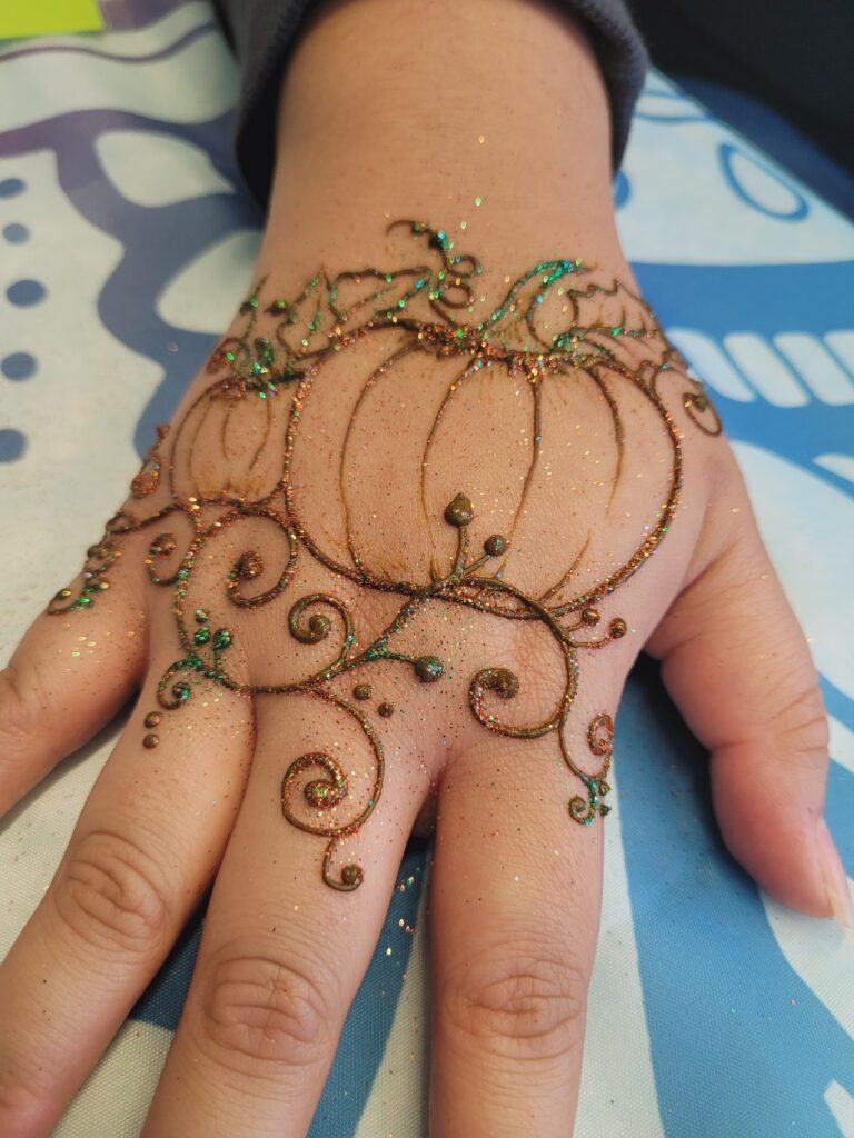 Closeup of a pumpkin henna designs with swirls and glitter.