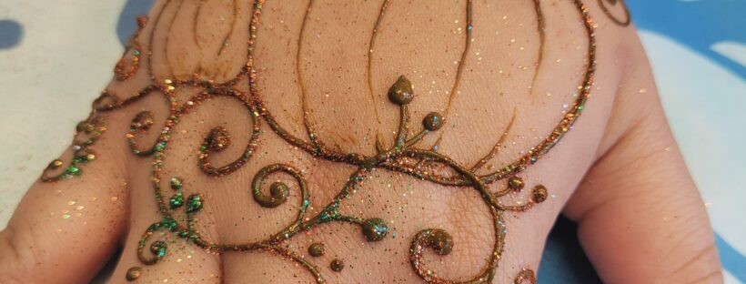 Closeup of a pumpkin henna designs with swirls and glitter.
