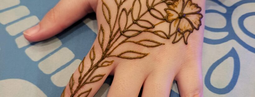 A Fall Flower henna design on the top of a hand